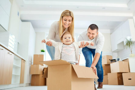 A happy family moves to a new apartment. Mother, father and child with boxes in the room of the new house.
